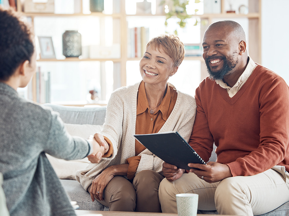 Two clients shaking hands with a professional while reviewing a document together